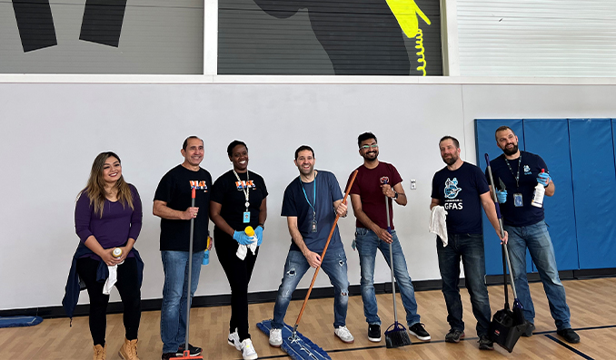 Volunteers cleaning our Downtown Clubhouse posing for a group picture in the gym.