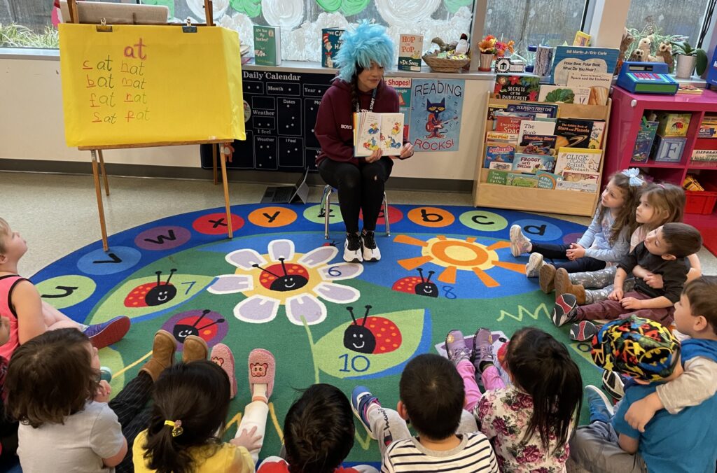 Teacher reading to kids on a colorful rug.